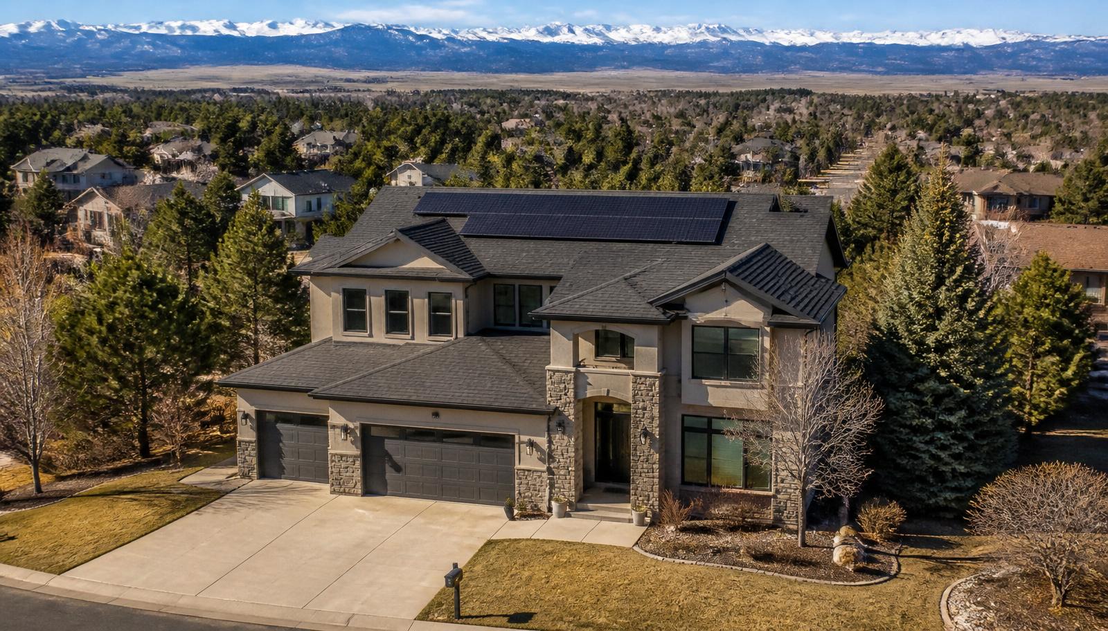 A Colorado Front Range detached family home with professionally installed rooftop solar panels, mountains in the background